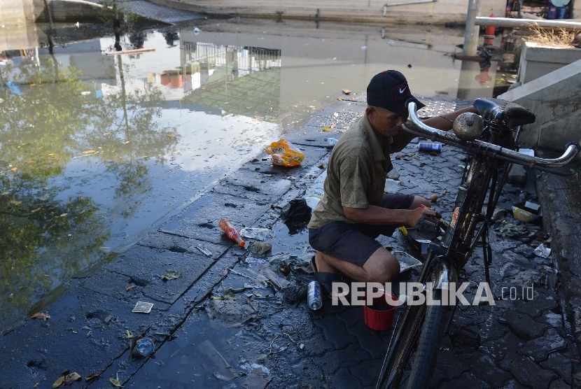  Seorang warga membersihkan sepedanya akibat banjir rob yang menggenangi wilayah Muara Baru, Jakarta Utara, Jumat (10/6).(Republika/Raisan Al Farisi)