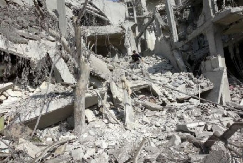 Seorang warga memeriksa bangunan yang hancur oleh serangan pasukan rezim Suriah di Arbeen, pinggiran kota Damsyik. 