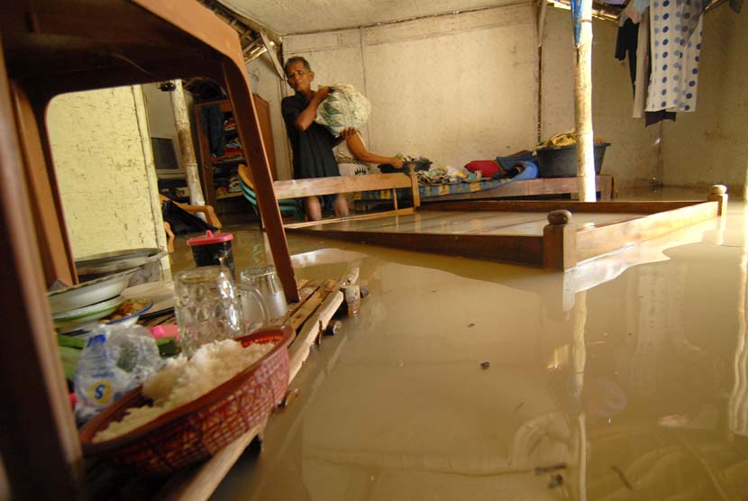Seorang warga memindahkan barang-barang ke tempat yang lebih tinggi saat banjir menggenangi rumah di Lamongan, Jawa Timur (ilustrasi) 