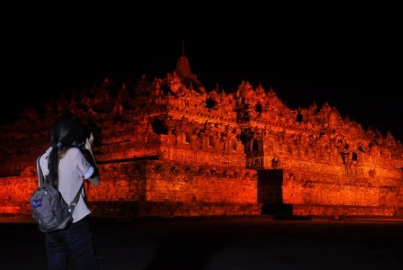 Seorang warga memotret candi Borobudur yang disinari dengan warna oranye saat berlangsung kampanye Anti Kekerasan Terhadap Perempuan di Taman Wisata Candi (TWC) Bororbudur, Magelang, Jateng, Sabtu (9/12). Kegiatan yang diselenggarakan oleh UN Women (Badan Perserikatan Bangsa-Bangsa untuk kesetaraan gender dan pemberdayaan perempuan) dengan TWC Borobudur tersebut mengusung tema 