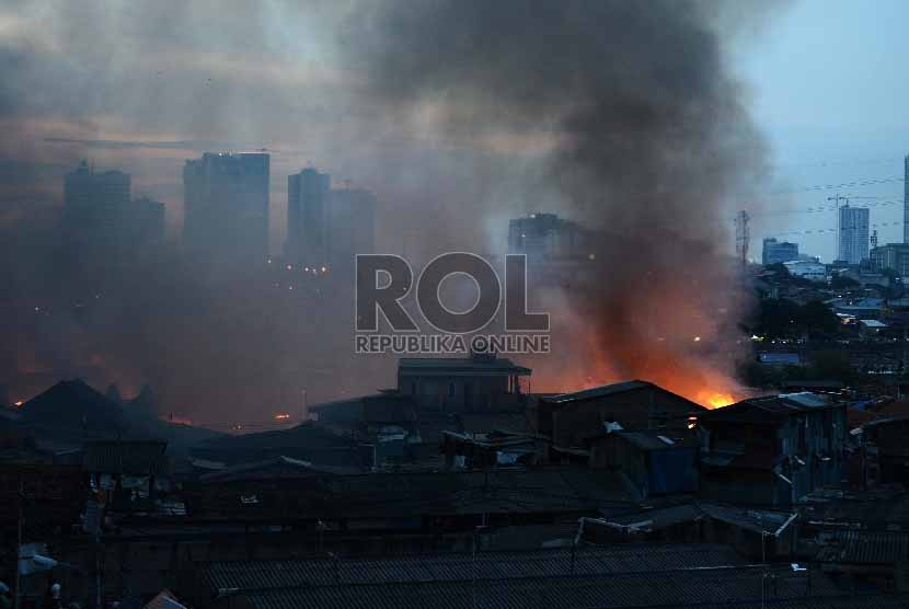 Seorang warga memotret kebakaran yang terjadi Gang Rotan, Pasar Kambing, Tanah Abang, Jakarta Pusat, Kamis (5/3). 