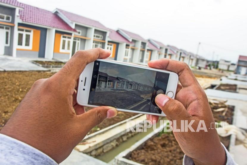 Seorang warga memotret perumahan di kawasan Majalaya, Karawang, Jawa Barat, Rabu (9/2/2022). Kementerian Pekerjaan Umum dan Perumahan Rakyat mencatat realisasi Program Sejuta Rumah pada 2021 mencapai 1.105.707 unit rumah di seluruh Indonesia. 