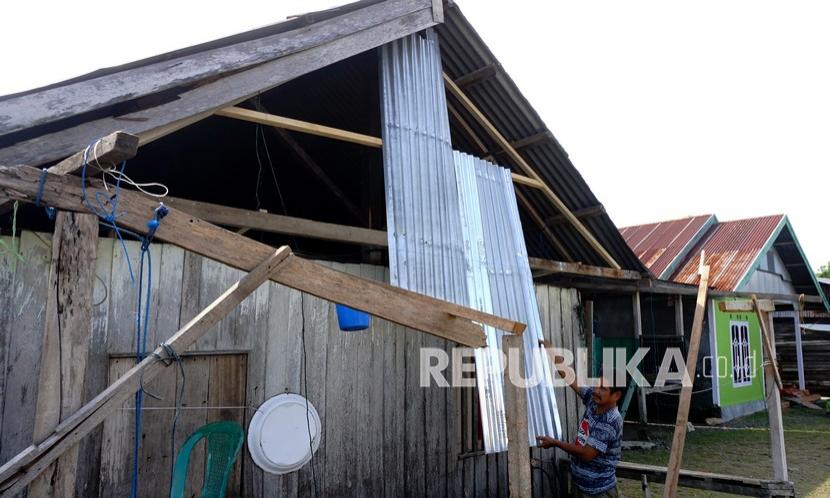 Seorang warga memperbaiki atap rumahnya yang rusak akibat angin kencang di Desa Papalang, Kecamatan Papalang, Mamuju, Sulawesi Barat.