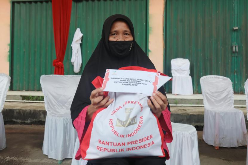 Seorang warga memperlihatkan amplop yang berisikan dana Bantuan Langsung Tunai (BLT) Minyak Goreng di Pasar Rakyat Angso Duo Baru, Kota Jambi, Kamis (7/4).