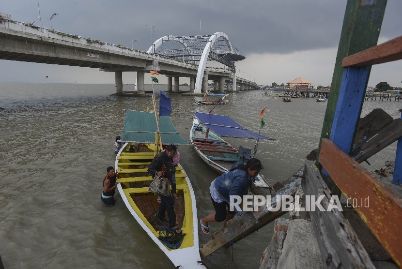 Seorang warga menaiki dermaga dengan lata belakang Jembatan Suroboyo yang berada di Kenjeran, Surabaya, Jawa Timur, Kamis (12/1).
