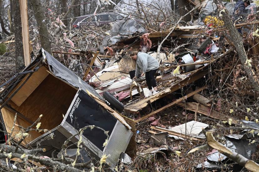 Seorang warga mencari barang-barang di reruntuhan rumah mobil ayahnya yang hancur akibat diterjang badai tornado.