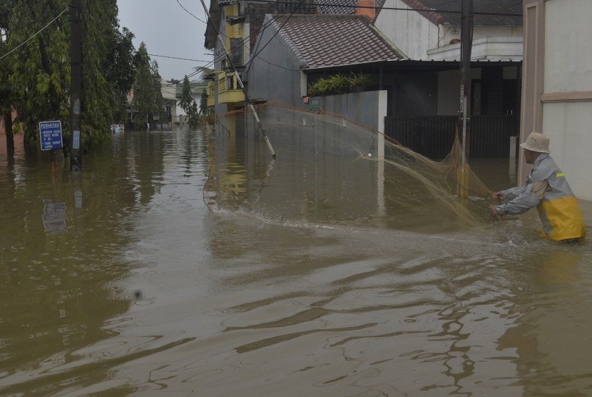 Seorang warga mencari ikan dengan jalan ketika terjadi banjir di Kompleks IKIP Jati Bening, Bekasi, Senin (20/2). 