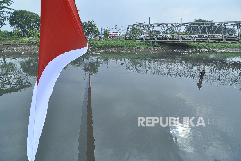 Seorang warga mencari ikan di bantaran Sungai Citarum dengan latar bendera merah putih di atas Sungai Citarum, kecataman Baleendah, Kabupaten Bandung, Jumat (12/8). 