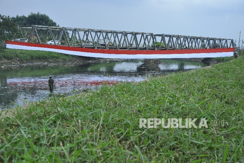 Seorang warga mencari ikan di bantaran Sungai Citarum dengan latar bendera merah putih di atas Sungai Citarum, kecataman Baleendah, Kabupaten Bandung, Jumat (12/8).