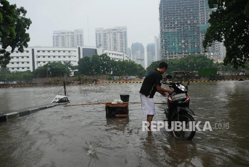  Seorang warga mencuci motornya di depan under pass rumah susun Kemayoran Jakarta yang ditutup dan tidak dapat dilalui karena terendam banjir, Selasa (21/2)