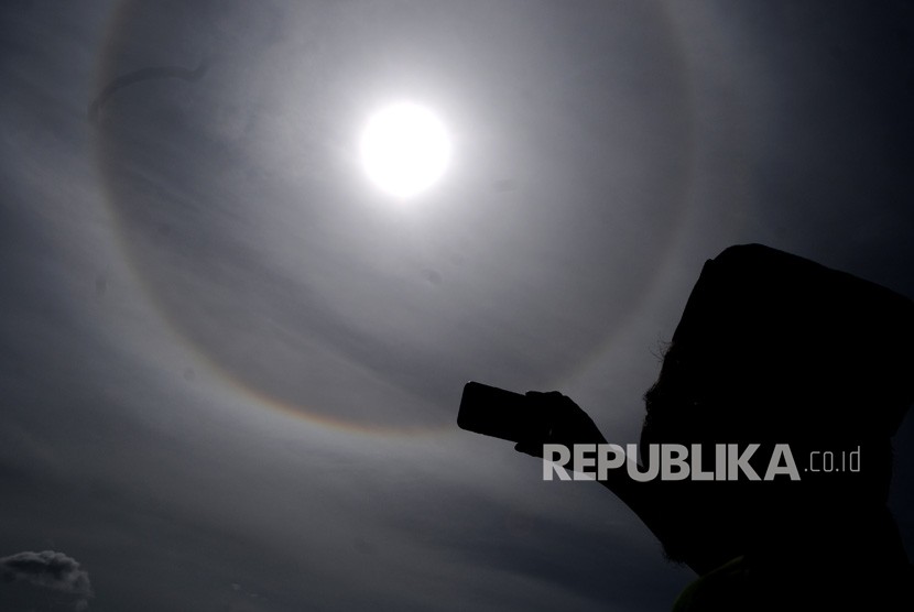 Seorang warga mengabadikan fenomena halo matahari di Desa Cibadak, Lebak, Banten, Selasa (11/2/2020).