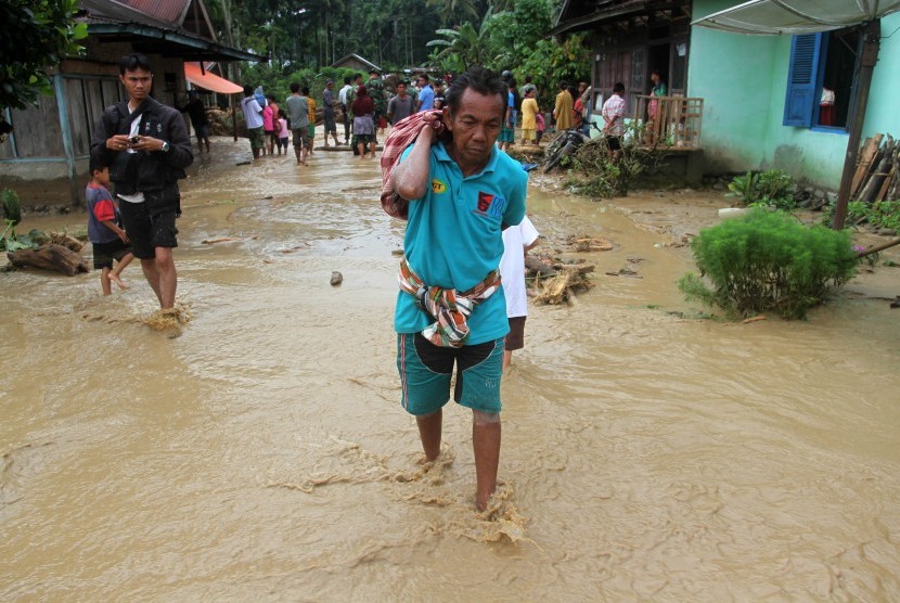 Seorang warga mengangkat barang-barang yang masih bisa diselamatkan untuk mengungsi, akibat banjir (ilustrasi).