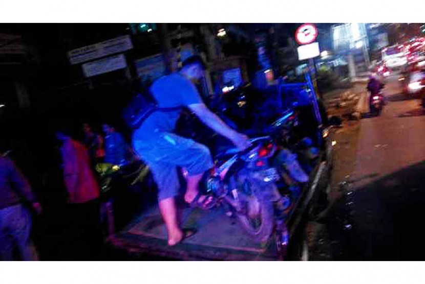 Seorang warga mengangkut motor yang ditabrak mobil. (Ilustrasi)