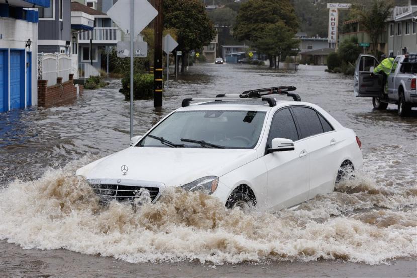  Seorang warga mengarungi banjir di Aptos Beach drive di Aptos, California, AS, Sabtu (14/1/2023).Gubernur California Gavin Newsom mengumumkan keadaan darurat akibat badai musim dingin. Banyak kabupaten California berada di bawah peringatan banjir. 
