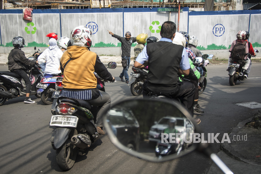 Seorang warga mengatur lalu lintas di persimpangan kawasan Tebet Timur, Jakarta, Senin (24/7). 