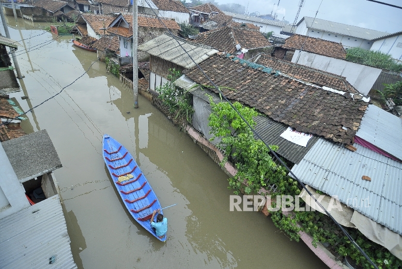 Seorang warga mengayuh perahu saat banjir di Desa Cieunteung, Kecamatan Baleendah, Kabupaten Bandung, Senin (3/10).