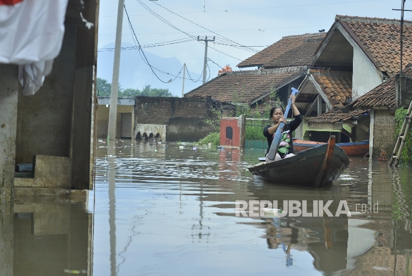 Seorang warga mengayuh perahu saat banjir di Desa Cieunteung, Kecamatan Baleendah, Kabupaten Bandung, Senin (3/10).