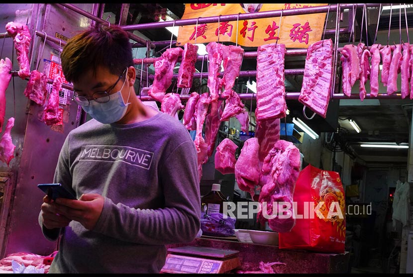Seorang warga mengenakan masker di depan kios daging sebuah pasar di Hong Kong, Kamis, (6/2). Warga memborong berbagai kebutuhan dasar di toko-toko seiring merebaknya wabah virus corona dari China daratan.