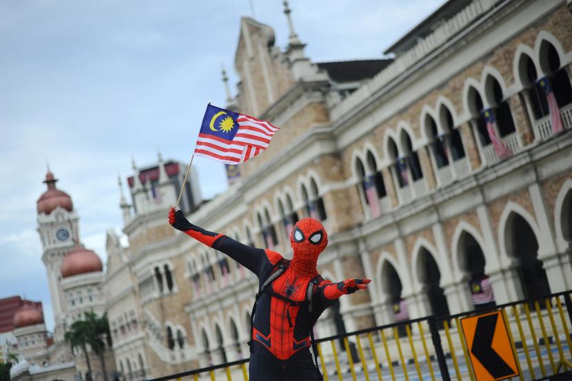 Seorang warga mengenakan pakaian Spiderman dengan bendera Jalur Gemilang untuk merayakan Hari Ulang Tahun (HUT) ke-64 Malaysia di Dataran Merdeka, Kuala Lumpur, Malaysia, Selasa (31/8/2021). 
