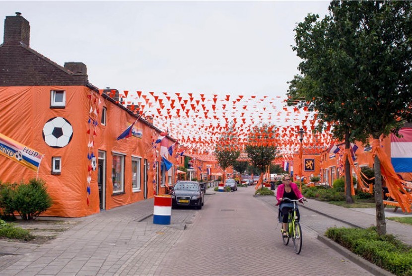 Seorang warga mengendarai sepeda di Goirle, Belanda, yang dihiasi dengan bendera, atribut, dan warna khas timnas Belanda. 
