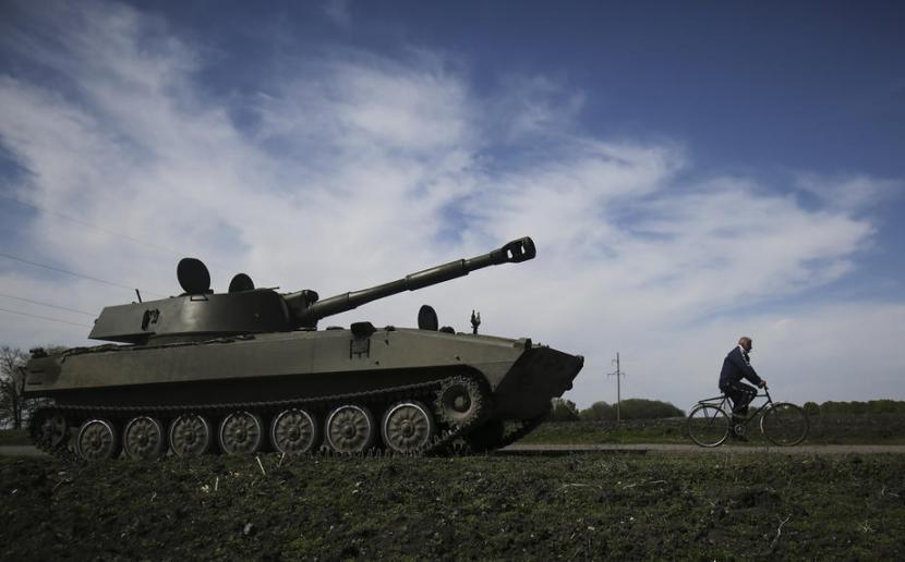 Seorang warga mengendarai sepeda melewati tank howitzer Ukraina, di Kharkiv, Ukraina, 7 Mei 2022. Menteri Pertahanan Jerman Christine Lambrecht mengatakan pelatihan tentara Ukraina untuk menggunakan howitzers Jerman akan segera selesai. 