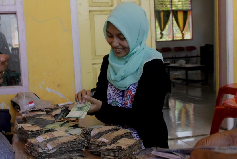 Seorang warga menggitung uang lusuh untuk ditukar dengan uang baru saat digelar Ekspedisi Kas Keliling Pulau Terluar, Terdepan dan Tertinggal (3T) di desa Tamher Timur, Pulau Kesui, Maluku, Jumat (2/11/2018).