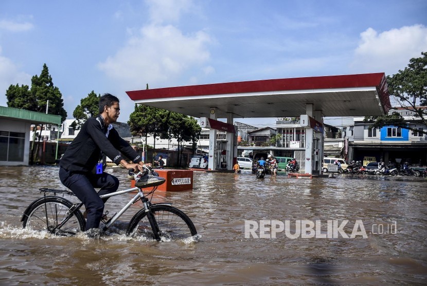 Seorang warga menggunakan sepeda melintasi genangan banjir di Jalan Raya Andir, Baleendah, Kabupaten Bandung, Jumat (24/1).