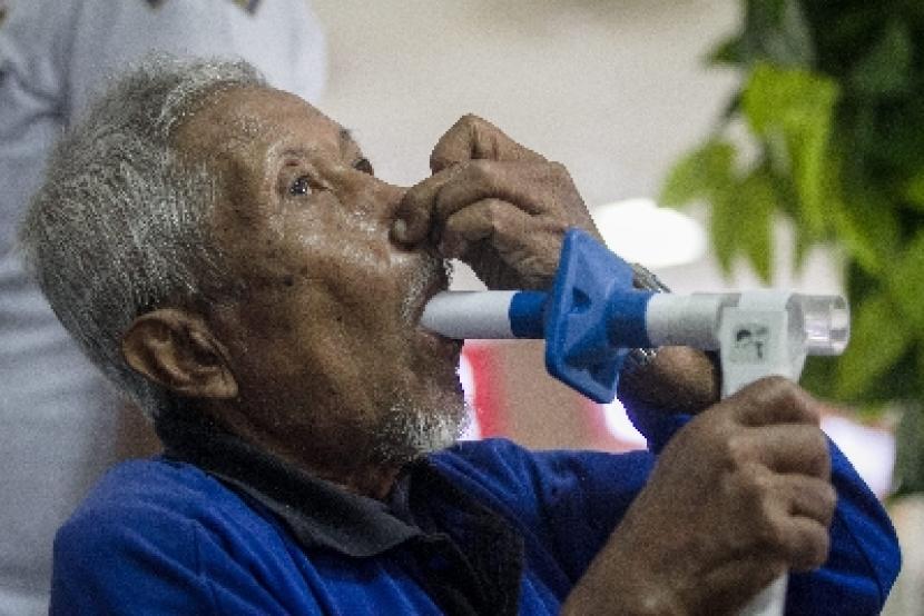 Seorang warga menggunakan spirometri, alat untuk menilai fungsi paru.