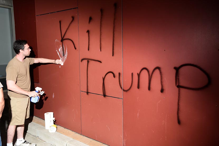 Seorang warga menghapus grafiti Kill Trump usai aksi unjuk rasa menentang kemenangan kandidat Presiden AS dari Partai Republik Donald Trump di Oakland, California.