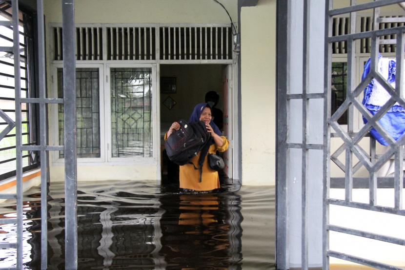 Seorang warga meninggalkan rumahnya yang dilanda banjir di Kelurahan Bumi Ayu Dumai, Riau, Kamis (28/10/2021). Hujan deras yang mengguyur Dumai tiga malam berturut-turut mengakibatkan bencana banjir di sejumlah kecamatan dengan dampak terparah di Kecamatan Dumai Selatan dan Dumai Timur.