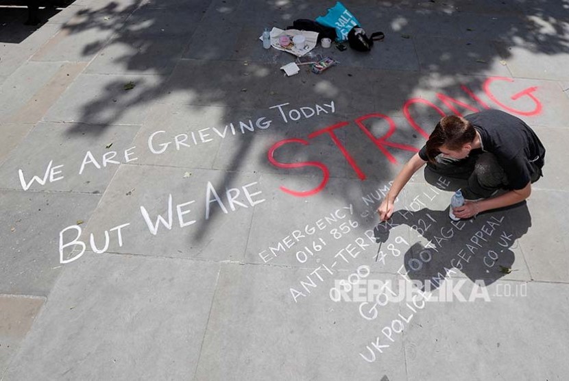 Seorang warga menuliskan ekspresi kesedihannya di pedestrian Manchester, Inggris (23/5)