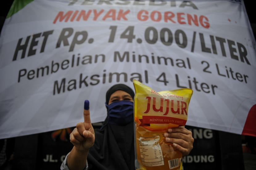 Seorang warga menunjukan minyak goreng serta jarinya yang telah ditandai tinta saat operasi pasar minyak goreng (ilustrasi).