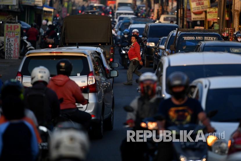 Seorang warga menyeberang jalan di tengah keramaian lalu lintas di Jalan Raya Sawangan, Depok.