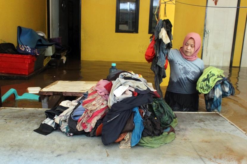 Seorang warga menyelamatkan pakaian saat banjir melanda permukiman kawasan Bidara Cina. Pemprov DKI Jakarta membersihkan kawasan Bidara Cina, Jaksel usai banjir.