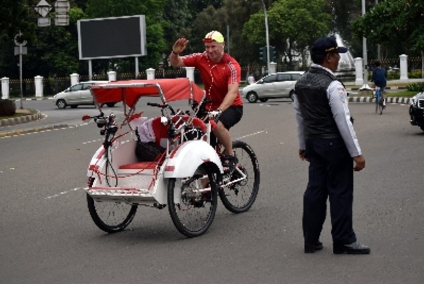 Seorang warga negara asing mengendarai becak melintasi Jalan Medan Merdeka Barat, Jakarta Pusat, Ahad (18/1).