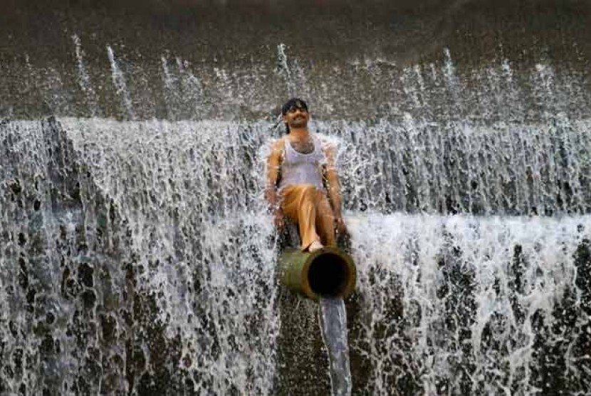 Seorang warga Pakistan mendinginkan diri di sungai di Islamabad.