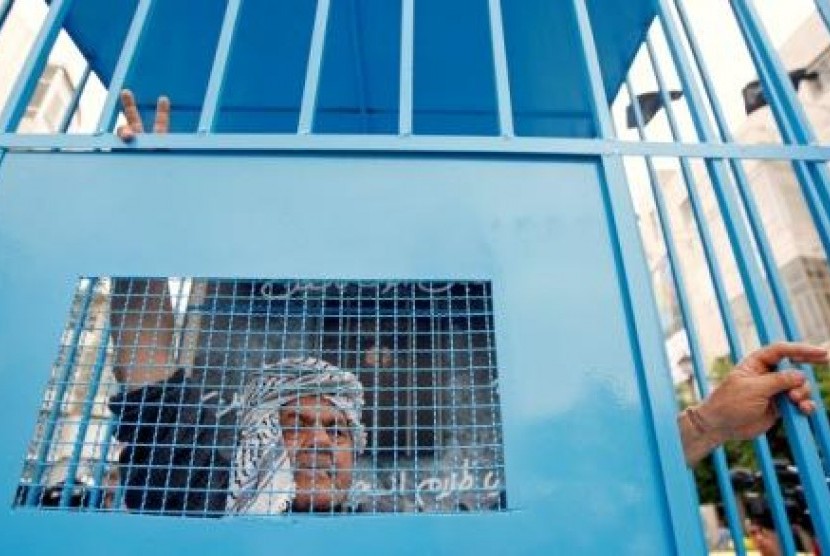  Seorang warga Palestina berdiri di belakang replika penjara, saat berunjuk rasa mendukung aksi mogok makan tahanan Palestina dalam penjara Israel.