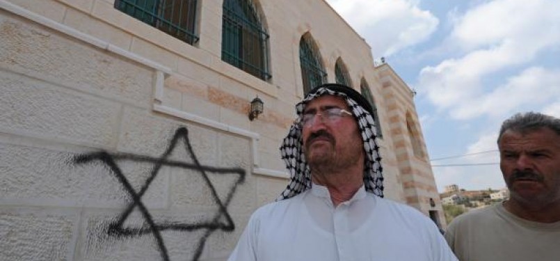 Seorang warga Palestina berdiri di depan masjid yang menjadi korban vandalisme Yahudi.