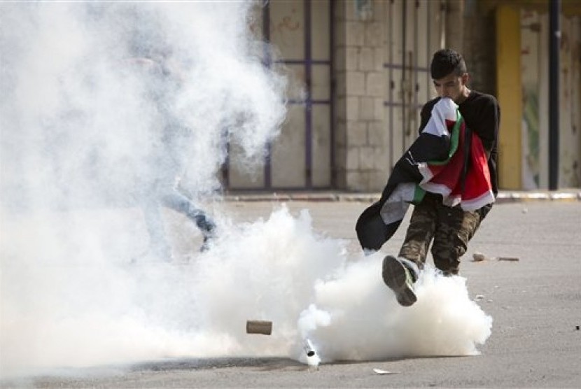 Seorang warga Palestina menendang gas air mata ke arah tentara Israel dalam kerusuhan di kompleks Masjid Al-Aqsa, Selasa (15/9). 