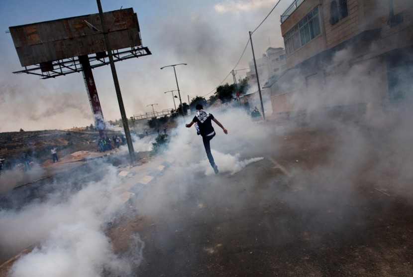  Seorang warga Palestina menendang tabung gas air mata yang ditembakkan oleh pasukan penjajah Israel dalam bentrokan yang terjadi dekat penjara militer, saat memperingati 64 Tahun Hari Nakba dekat kota Ramallah di Tepi Barat Palestina, Selasa (15/5).  (Ber