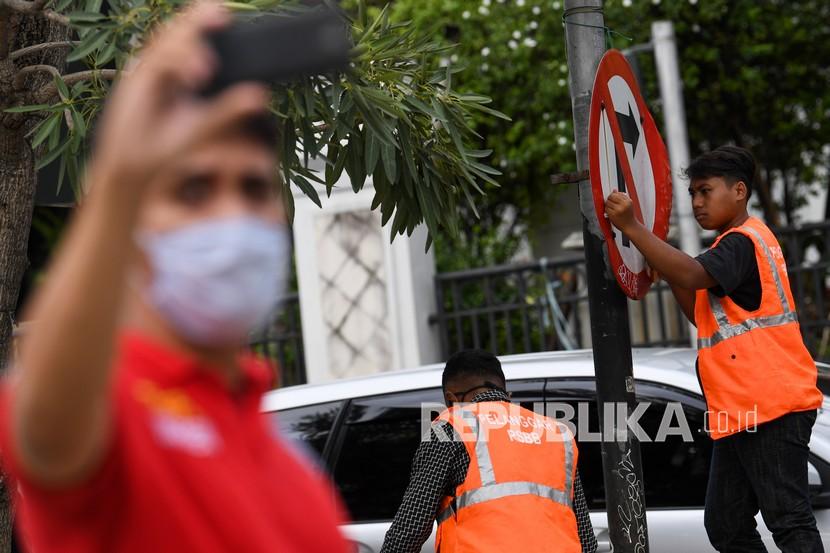 Seorang warga pelanggar protokol kesehatan membersihkan papan penunjuk jalan saat Operasi Yustisi Protokol Kesehatan COVID-19 di kawasan Mampang, Jakarta Selatan.