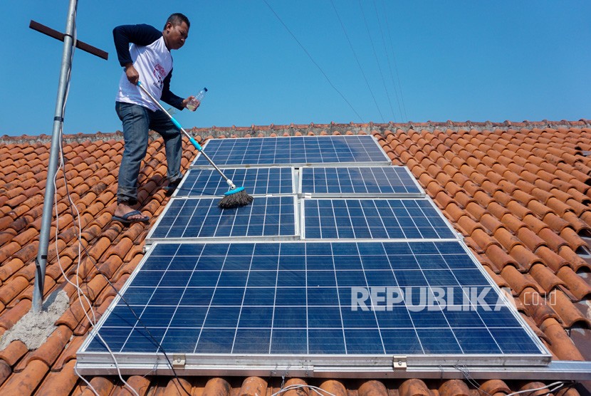 Seorang warga pemilik panel surya membersihkan panel Pembangkit Listrik Tenaga Surya (PLTS) Atap rumahnya (ilustrasi). Kementerian ESDM menyebut, pengguna PLTS Atap baru sekitar 3.000 pelanggan dengan daya sekitar 21 megawatt (MW).