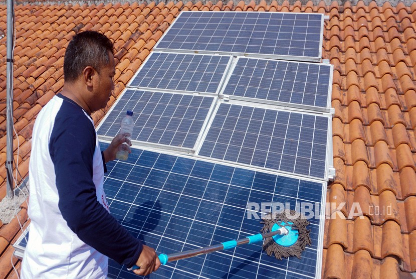 Seorang warga pemilik panel surya membersihkan panel Pembangkit Listrik Tenaga Surya (PLTS) di atap rumahnya di Sragi, Kabupaten Pekalongan, Jawa Tengah, Ahad (1/9). 