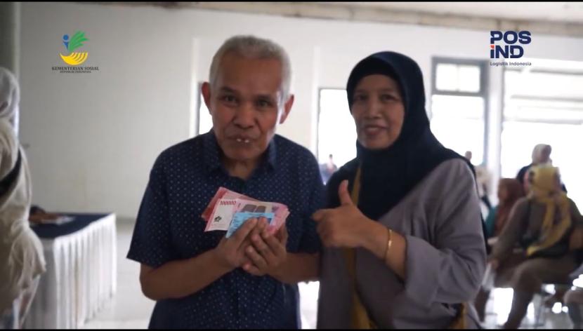 Seorang warga penerima PKH menunjukkan uang yang diterima melalui Pos Indonesia. 