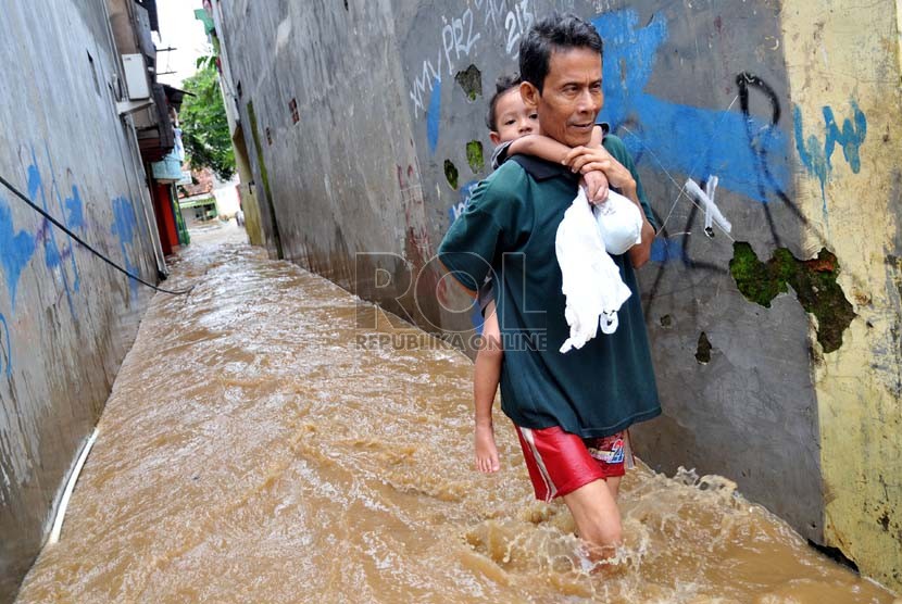  Seorang warga sambil menggendong anaknya melintasi banjir di Jalan Kampung Melayu Kecil, Kelurahan Bukit Duri, Kecamatan Tebet, Jakarta, Selasa ( 5/3).  (Republika/Prayogi)