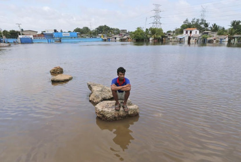 Seorang warga Sri Lanka duduk di potongan beton di wilayahnya yang terendam banjir (Ilustrasi)