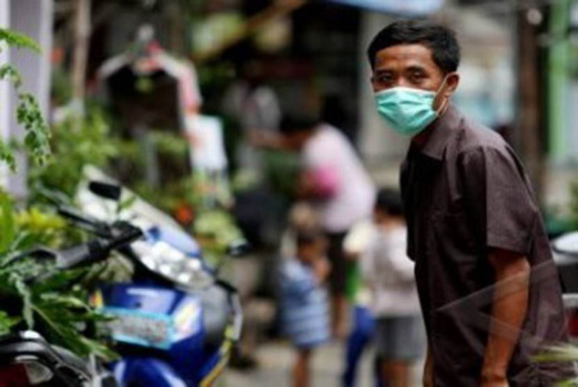 Seorang warga Sunter memakai masker setelah seorang pemuda berinisial PDY meninggal dunia akibat terjangkit flu burung di Sunter Agung, Tanjung Priok, Jakarta Utara, Senin (9/1). 
