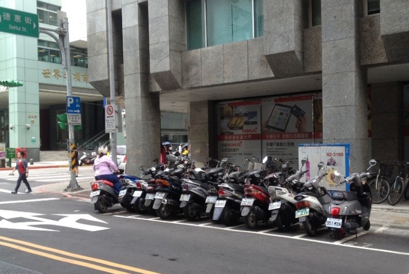 Seorang warga Taipei menyeberang di zebra cross, seorang lainnya memarkir motor dengan tertib di tempat yang telah disediakan.