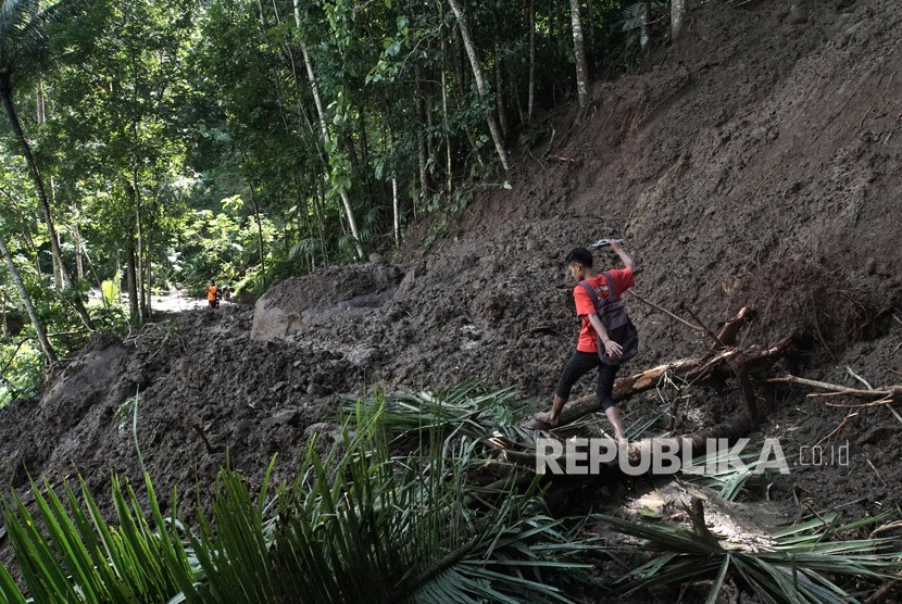 Seorang warga terpaksa melintasi jalan yang terkena longsor di Desa Cihonje, Gumelar, Banyumas, Jawa Tengah, Senin (18/12).