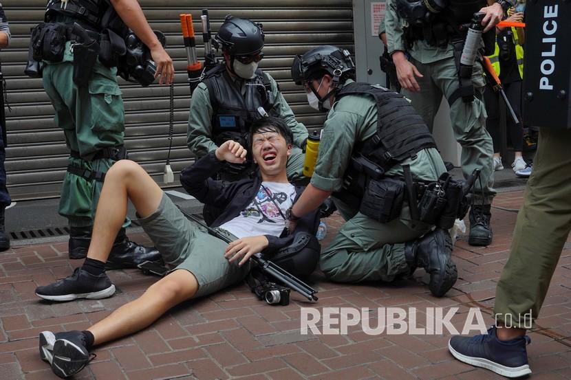 Seorang wartawan jatuh setelah disemprot dengan semprotan merica oleh polisi dalam sebuah protes di Causeway Bay selama pawai penyerahan tahunan di Hong Kong, Rabu, Juli. 1, 2020. Hong Kong menandai peringatan 23 tahun penyerahannya ke Cina pada tahun 1997, dan hanya satu hari setelah Cina memberlakukan undang-undang keamanan nasional yang menindak protes di wilayah tersebut. 